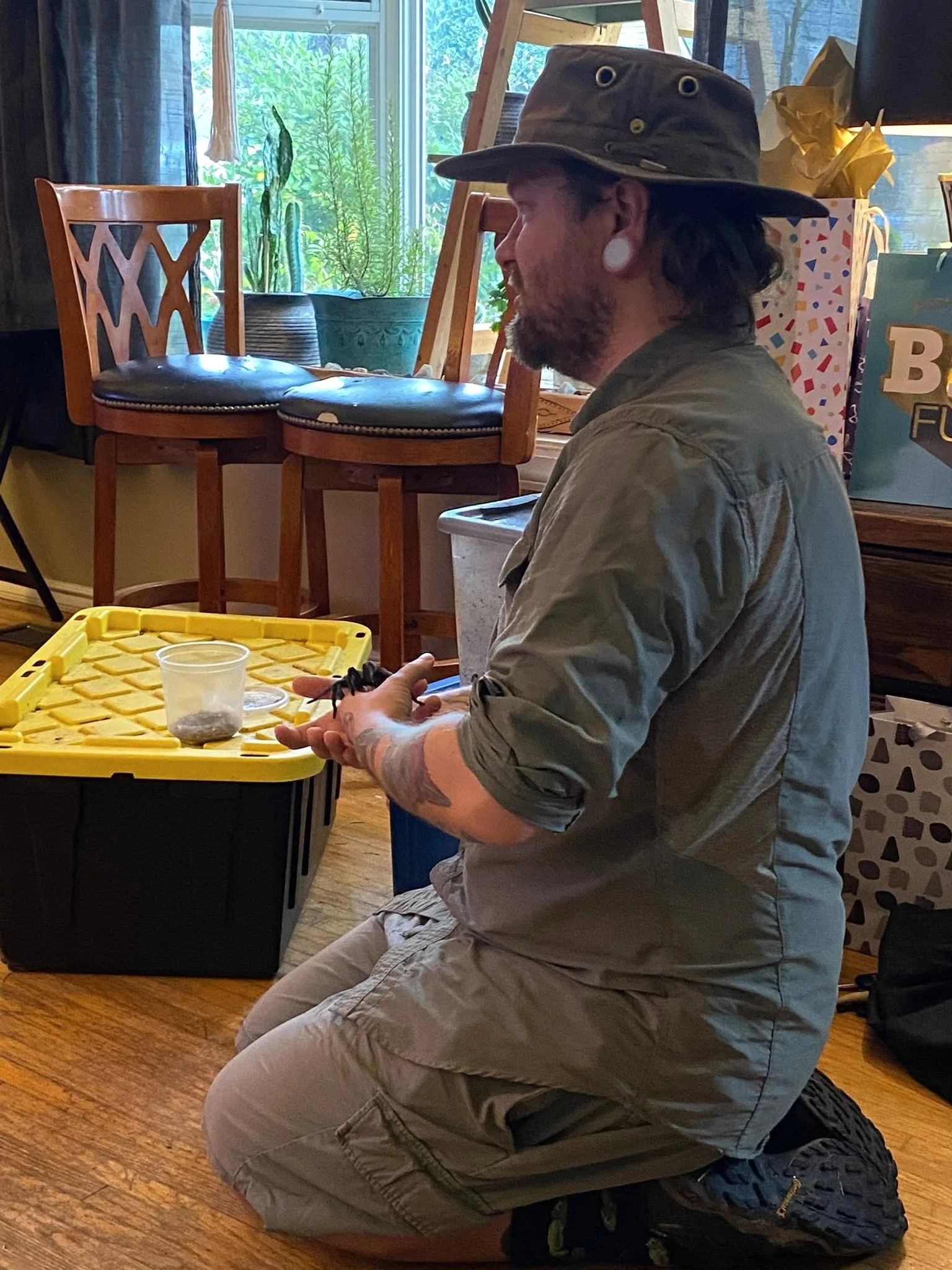 Kevin kneeling with a tarantula during an indoor presentation