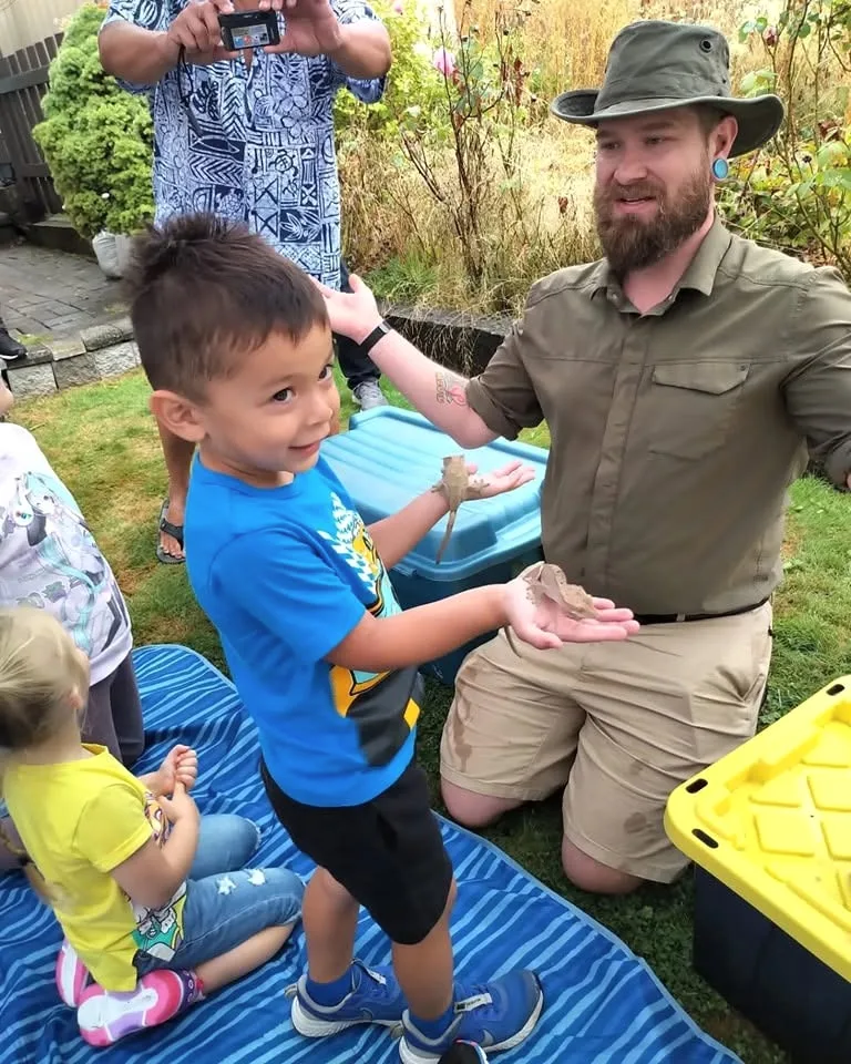 A child interacting with a tarantula alongside a presenter